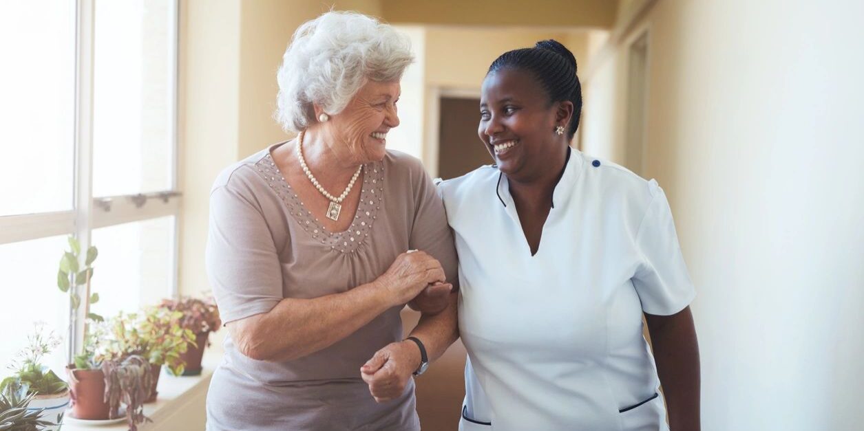 Assistant assisting an elder in hallway